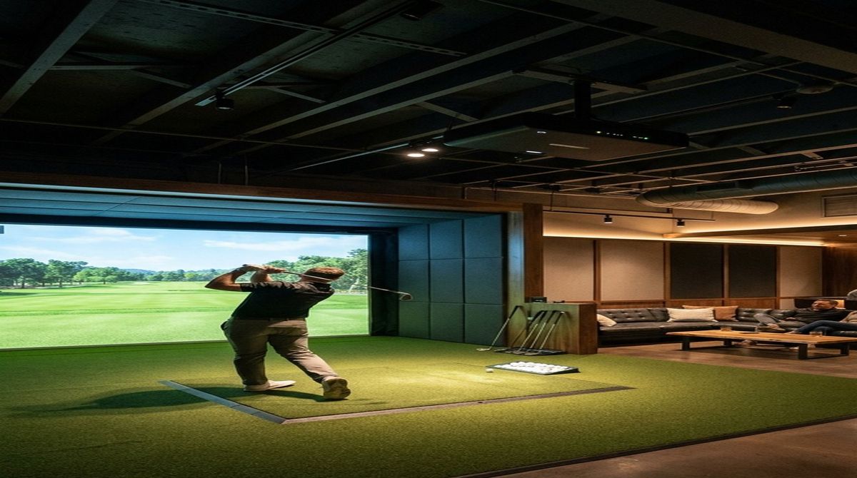 Golf simulator hitting zone illuminated under narrow beam ceiling spotlight